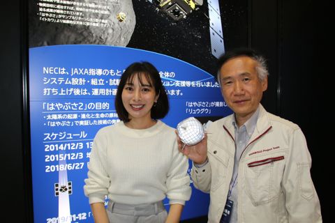 NEC宇宙事業広報の小笠原雅弘さん。
小笠原さんが手にしているのがターゲットマーカーのレプリカ。